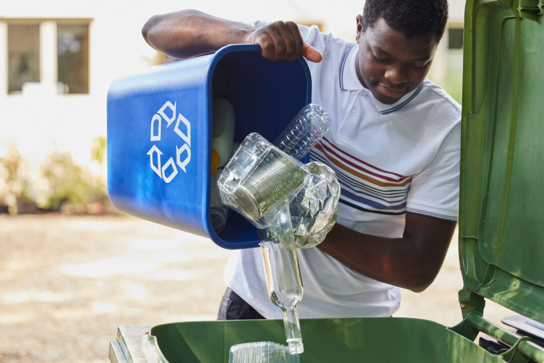 Man Emptying Household Recycling Into Green Bin